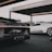 Two luxury sports cars are showcased in a modern, open garage. The foreground features a sleek black car with intricate tail light and exhaust details, while a white sports car stands in the background. The setting suggests a high-end automotive event or display.